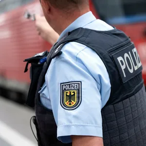 Bundespolizist steht an einem Bahnsteig vor einem Zug der Deutschen Bahn