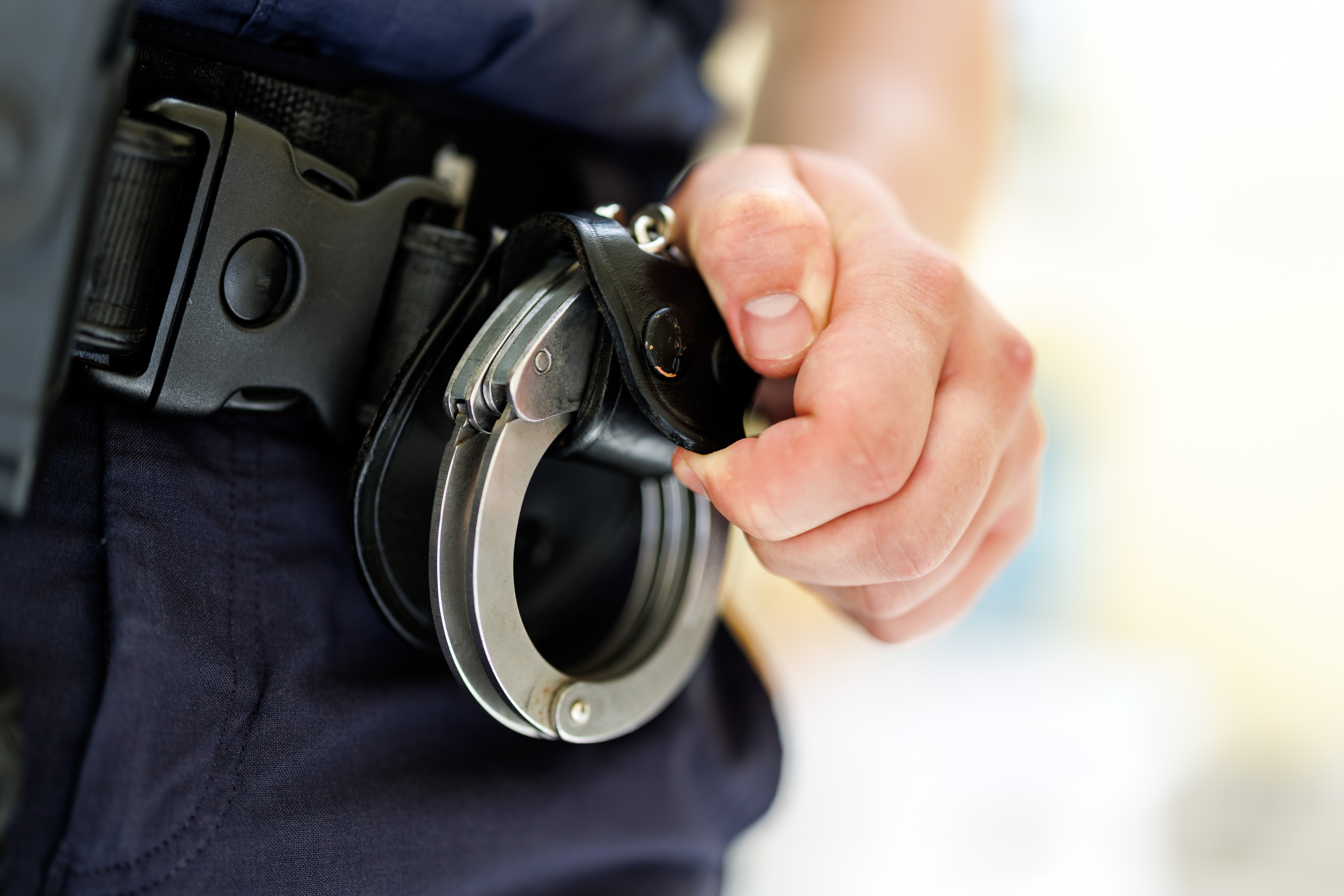 Ein Polizist hält Handschellen.