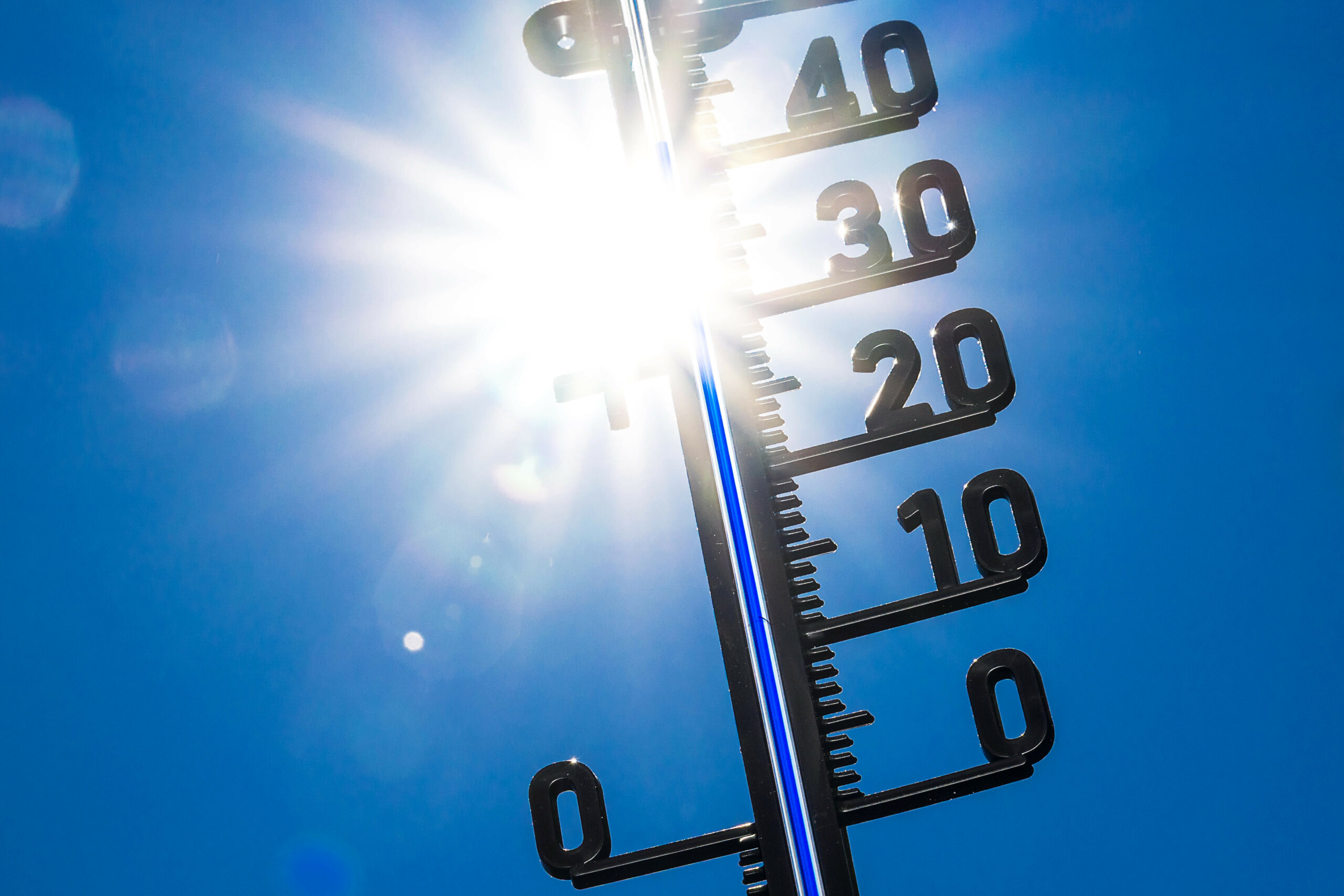 Thermometer mit greller Sonne im Hintergrund