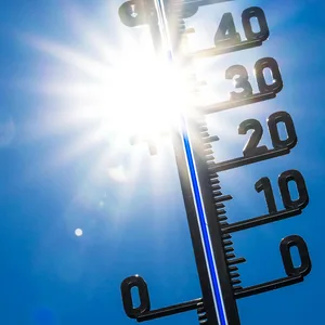 Thermometer mit greller Sonne im Hintergrund