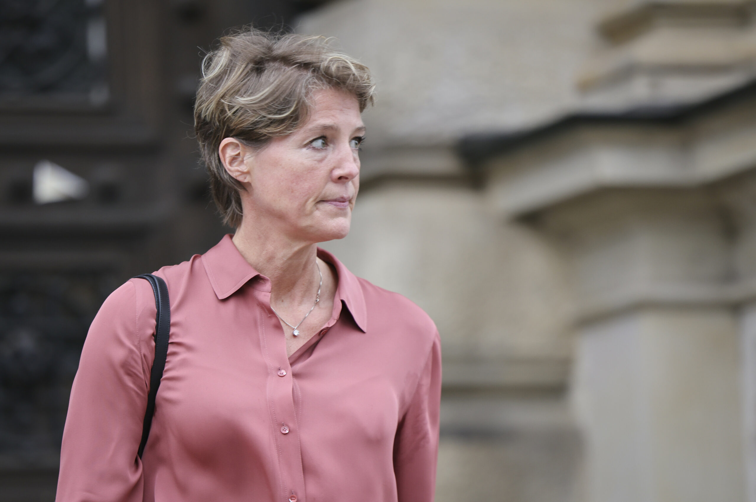 Frau in rosa Bluse vor Gerichtsgebäude