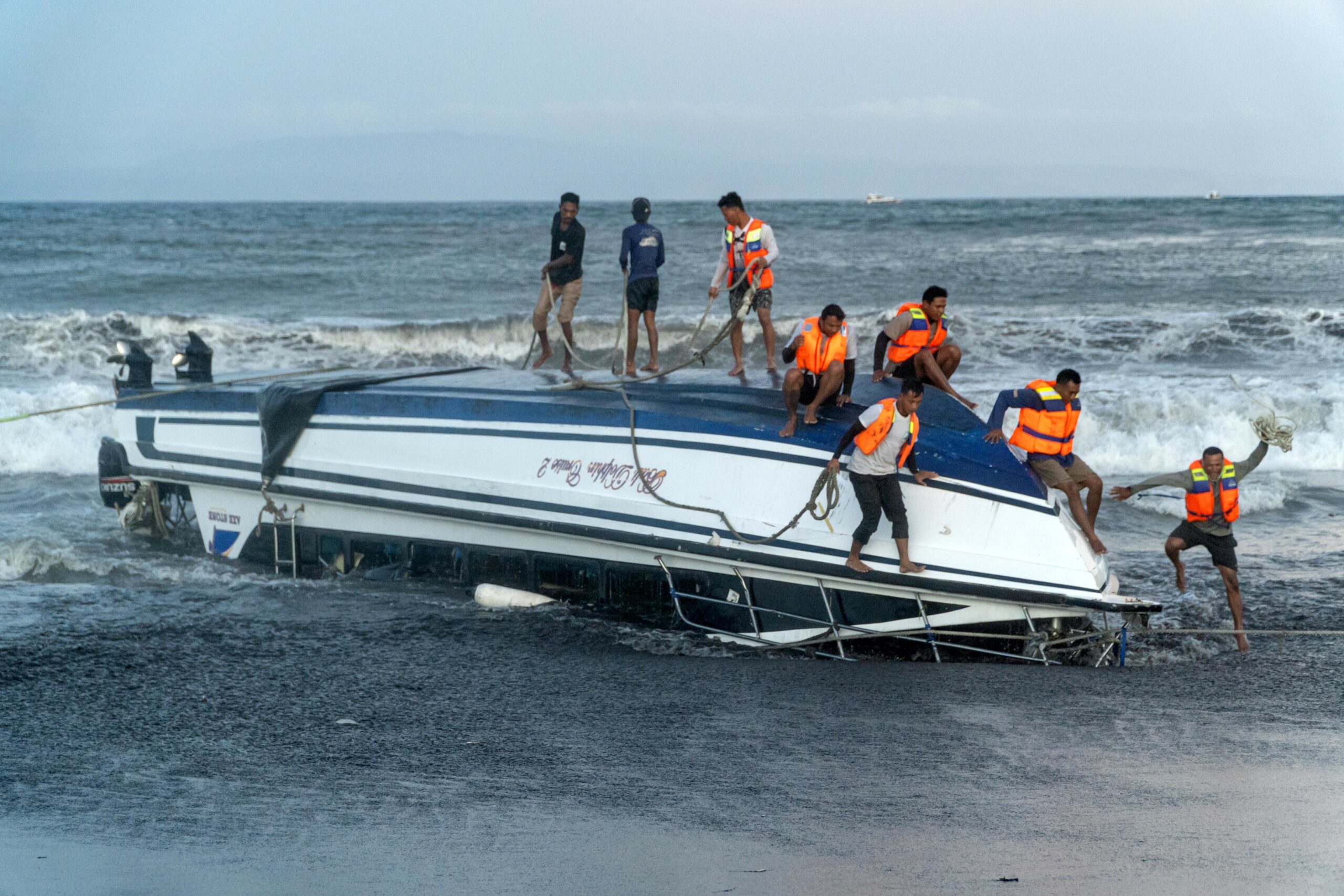 Menschen in Rettungswesten auf einem gekenterten Boot