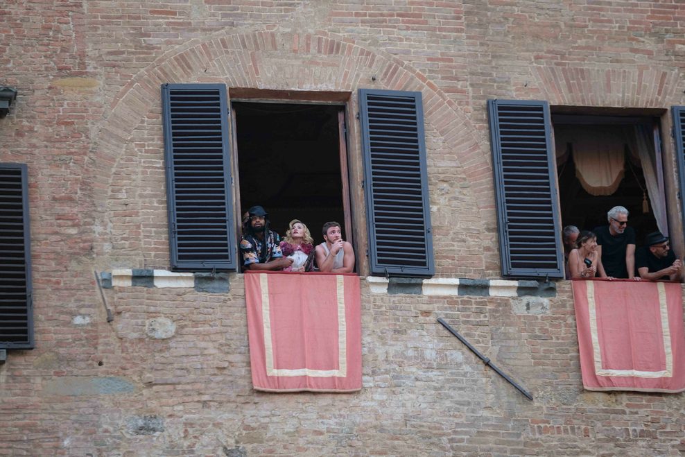US-Sängerin Madonna (2.v.l) steht an einem Fenster des Palazzo Pannocchieschi d’Elci zusammen weiteren Menschen und blickt auf die Piazza del Campo.