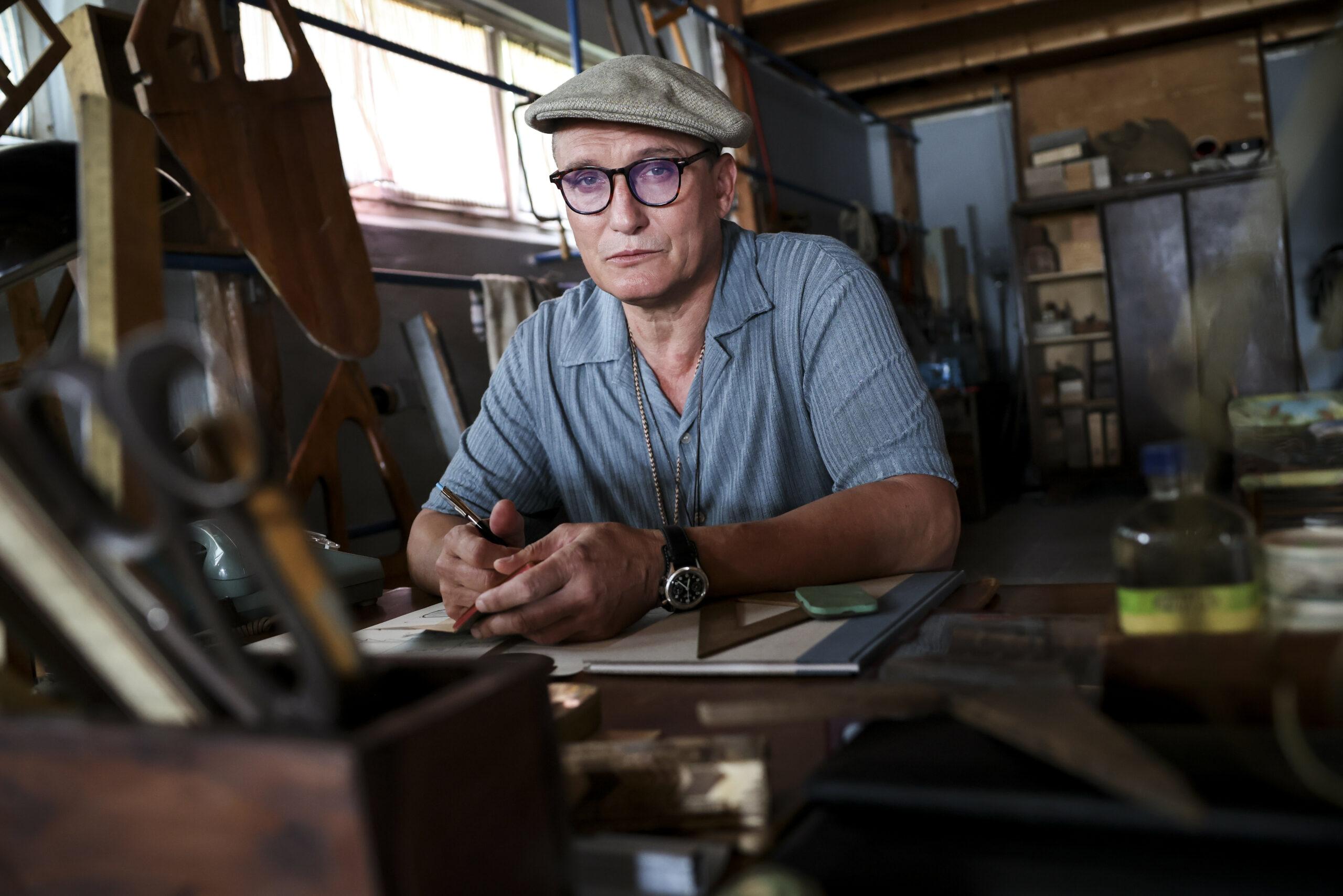 Oliver Masucci, Schauspieler in der Rolle als Rudertrainer Klaus Adam, sitzt am Set in seiner Werkstatt im Bootshaus des Ratzeburger Ruderclubs