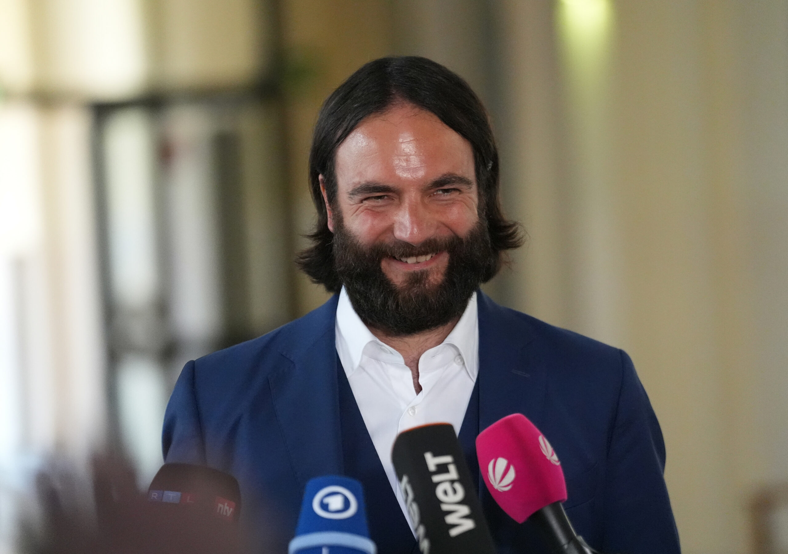 Mann mit dunklen Haaren vor Mikrofonen
