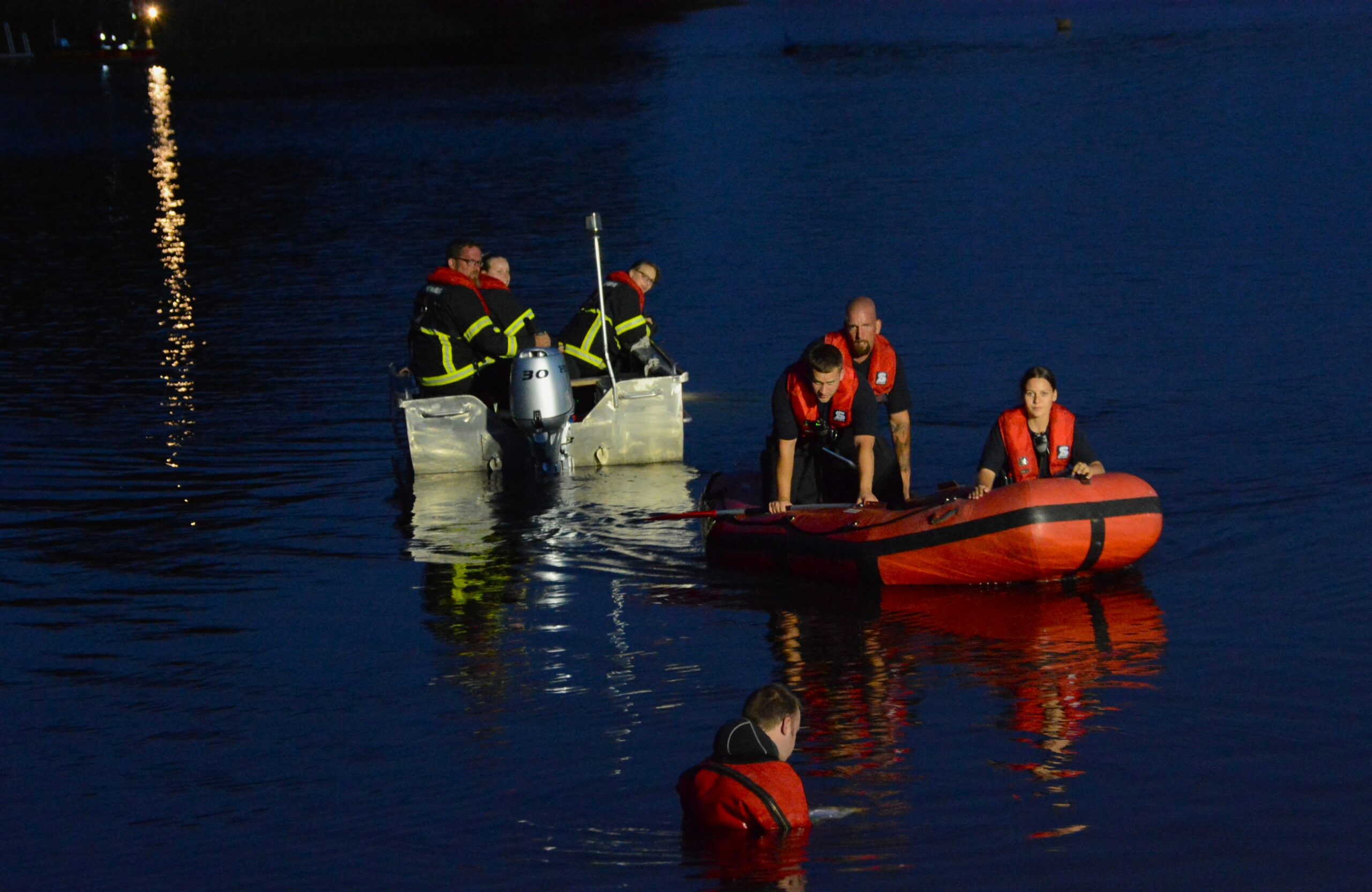 Einsatzkräfte der Feuerwehr sind auf Booten im Wasser und suchen den See ab.