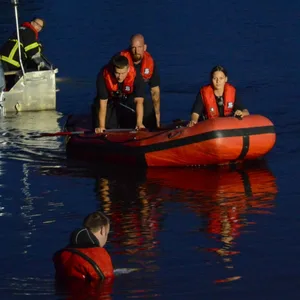 Einsatzkräfte der Feuerwehr sind auf Booten im Wasser und suchen den See ab.