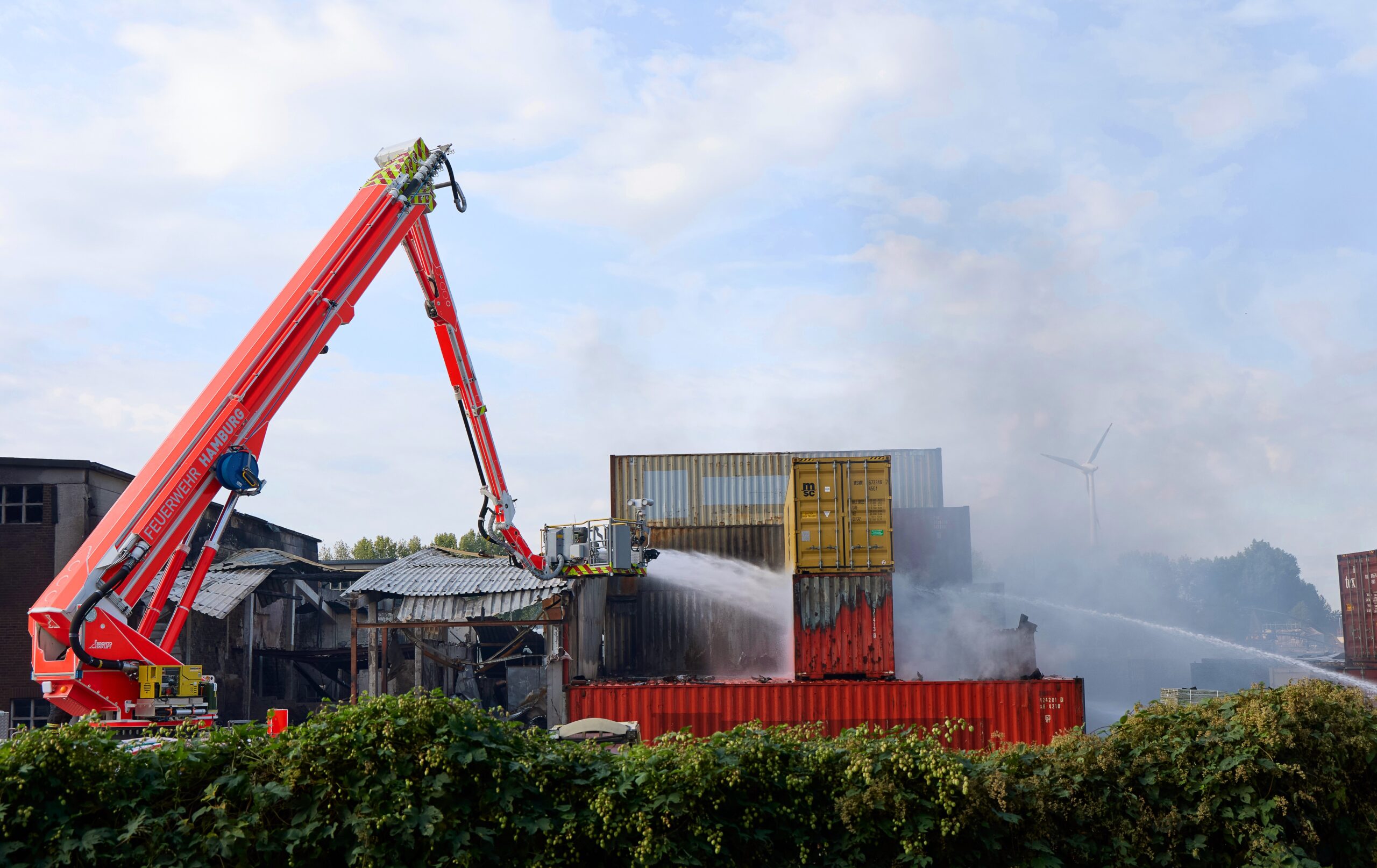Feuerwehrkräfte löschen am Mittwochmorgen Container auf dem Gelände einer Spedition auf der Veddel in Hamburg.