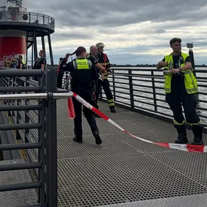 Polizisten und Einsatzkräfte der Feuwerwehr stehen an einem Leuchtfeuer an der Elbe in Hamburg.