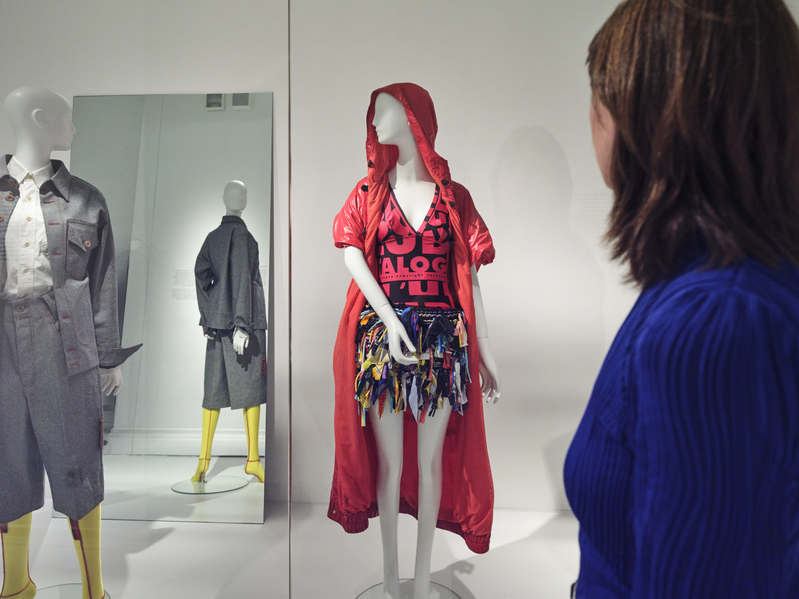 Eine Frau steht in einem Ausstellungsraum vor Schaufensterpuppen.