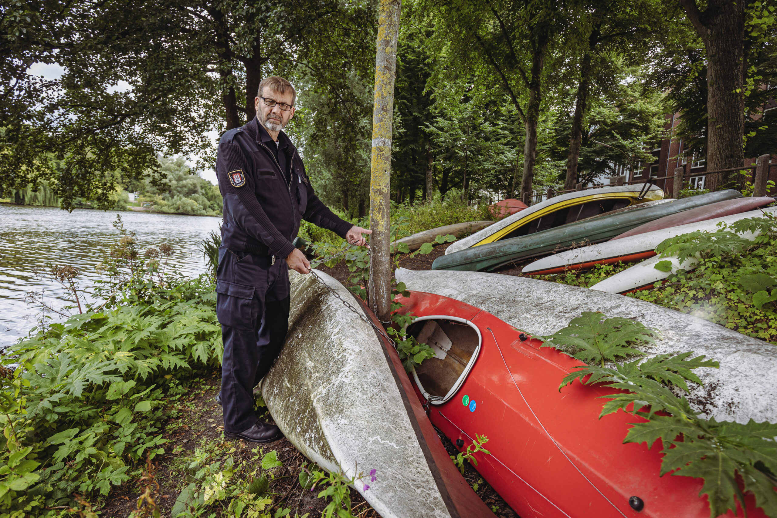Mann in dunkelblauer Uniform mit vielen Booten am Ufer