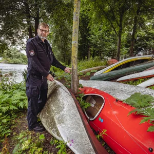 Mann in dunkelblauer Uniform mit vielen Booten am Ufer