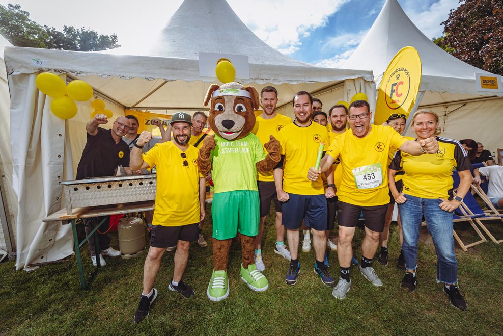 Der FC Deutsche Post posiert mit dem Staffelmaskottchen.