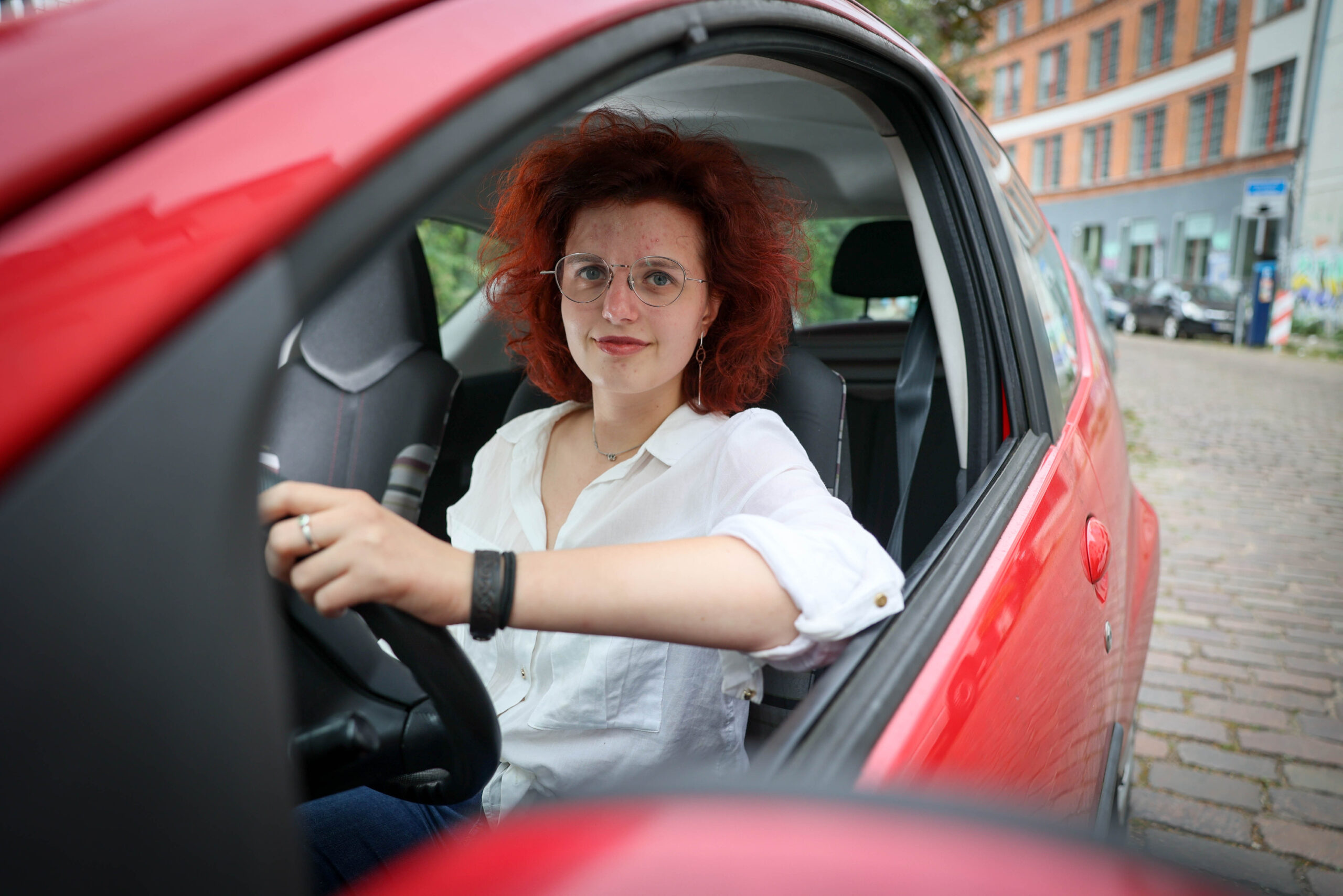 Eine Frau am Steuer eines roten Autos.