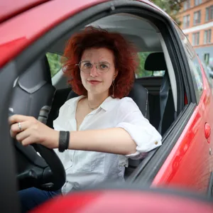 Eine Frau am Steuer eines roten Autos.