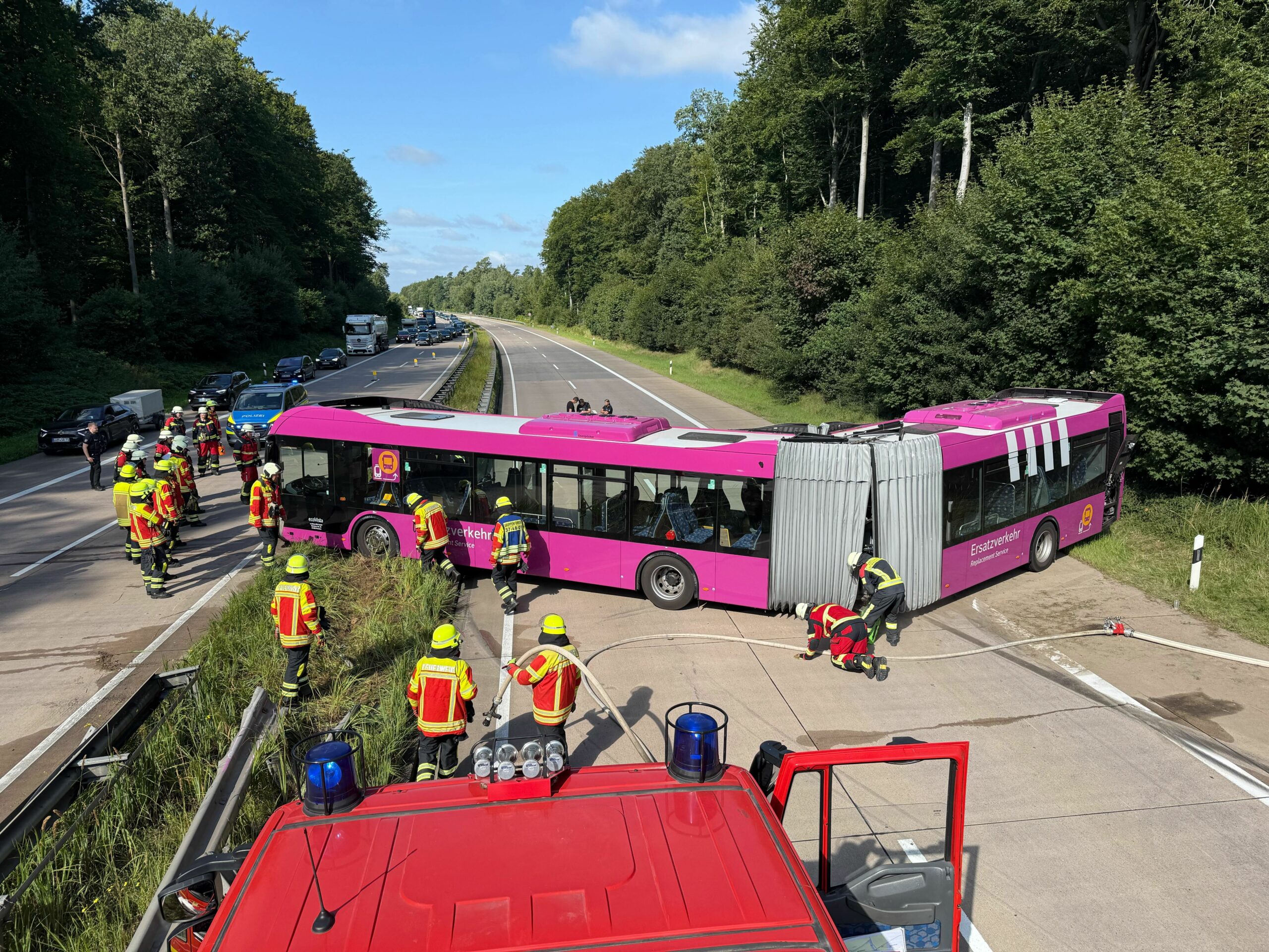 Pinker Bus steht quer auf Autobahn