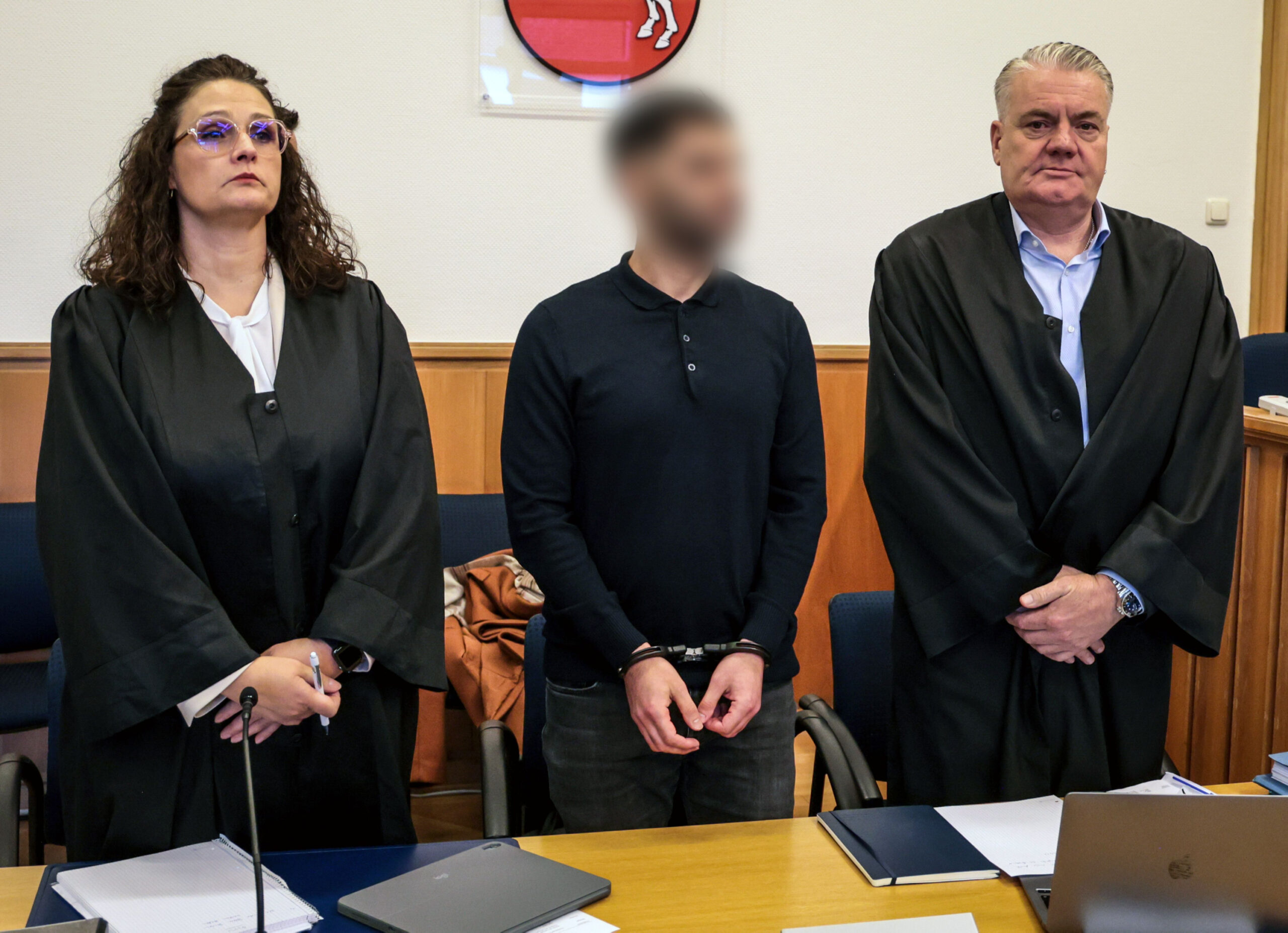 Der Angeklagte (M) steht zu Prozessbeginn zwischen seinen Anwälten im Landgericht.