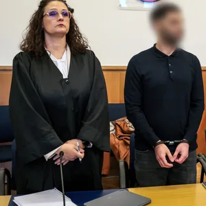 Der Angeklagte (M) steht zu Prozessbeginn zwischen seinen Anwälten im Landgericht.