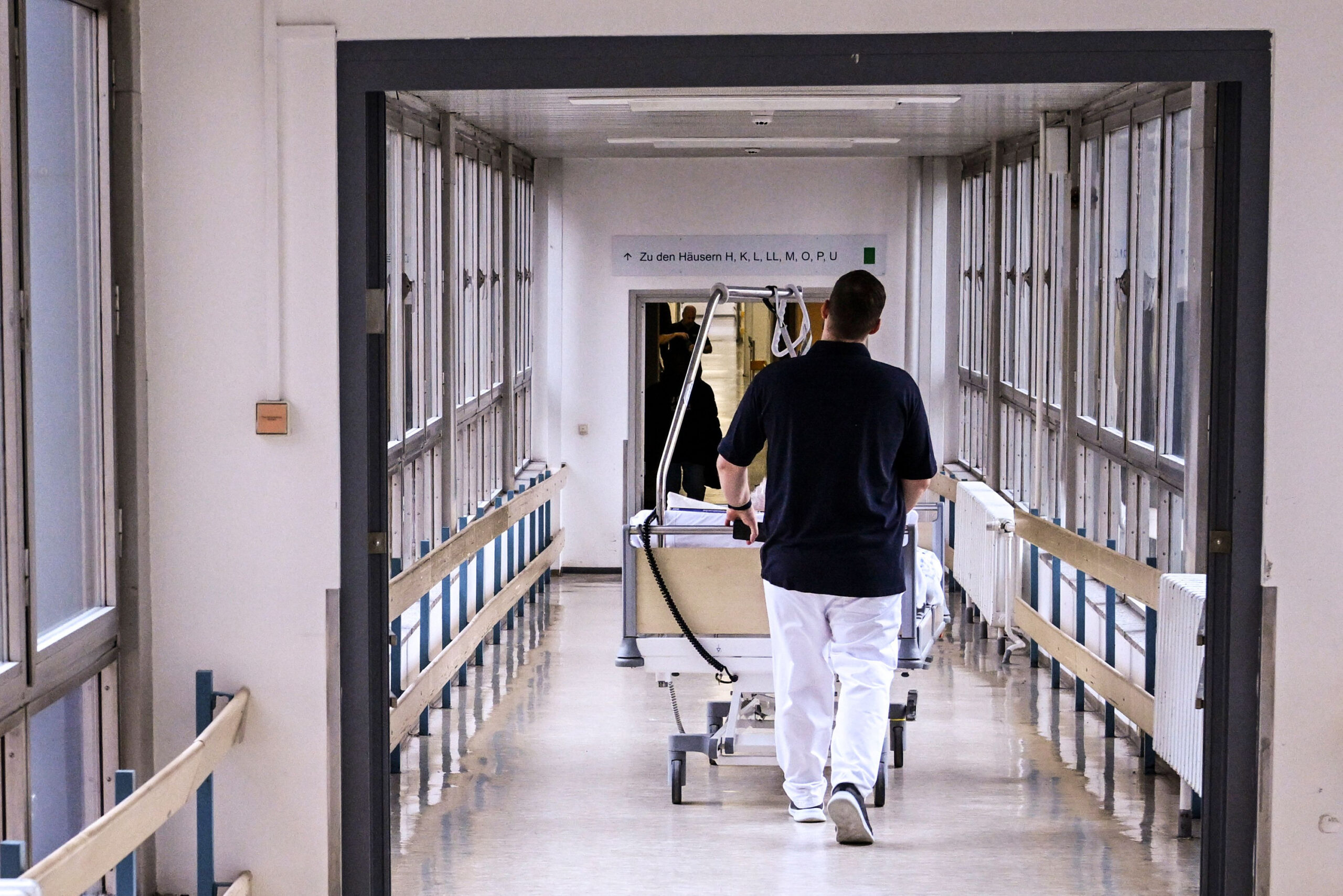 Ein Patientenbett wird durch den Flur einer Klinik geschoben.