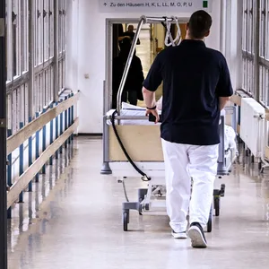 Ein Patientenbett wird durch den Flur einer Klinik geschoben.
