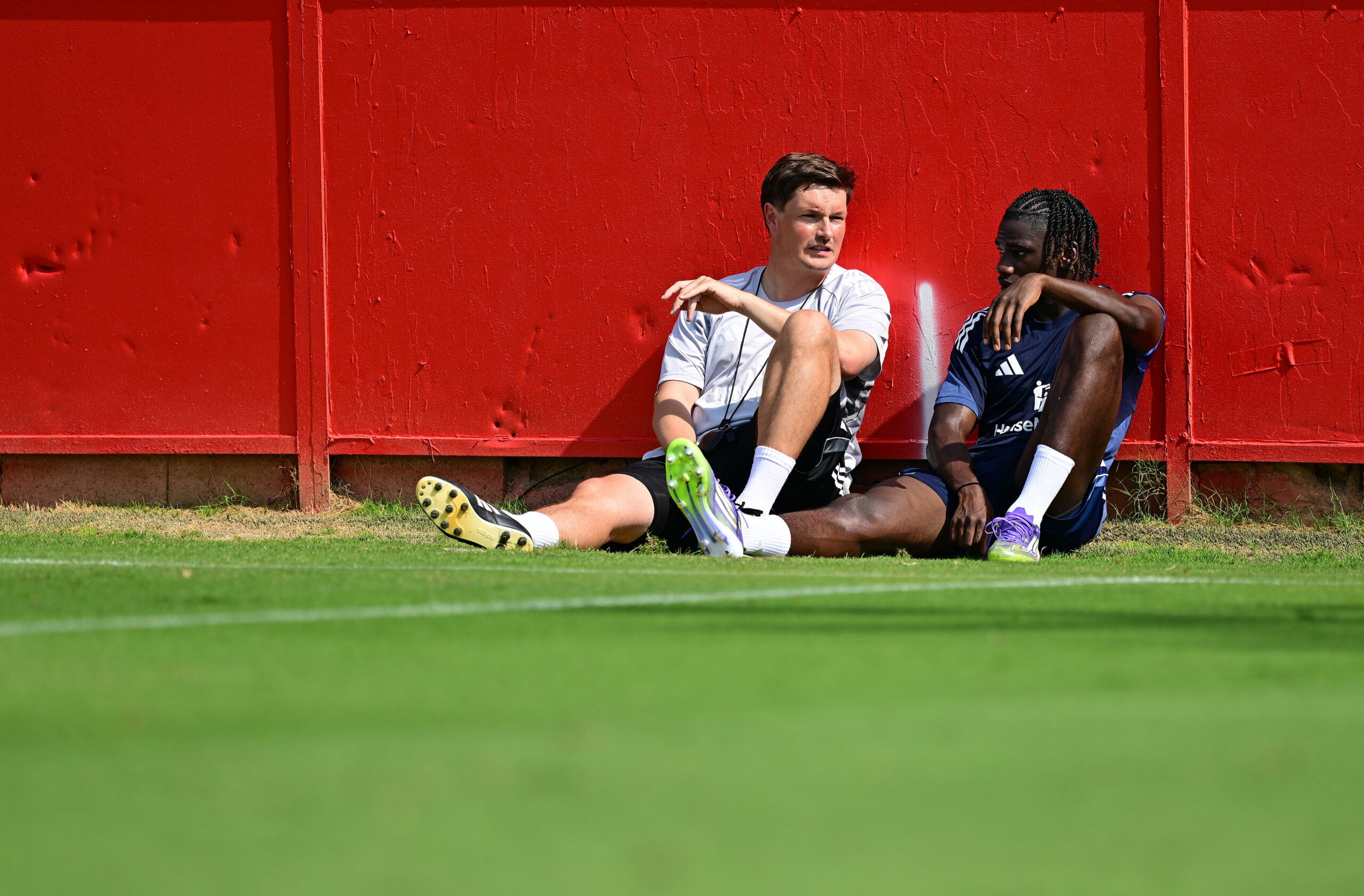 Merlin Polzin sitzt mit Fabio Baldé vor einer Wand am Spielfeldrand