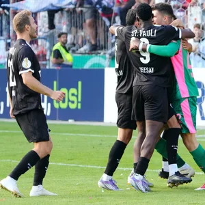 Die Mitspieler feiern St. Paulis Torwart Nikola Vasilj nach dem Elfmeterschießen gegen Norderstedt