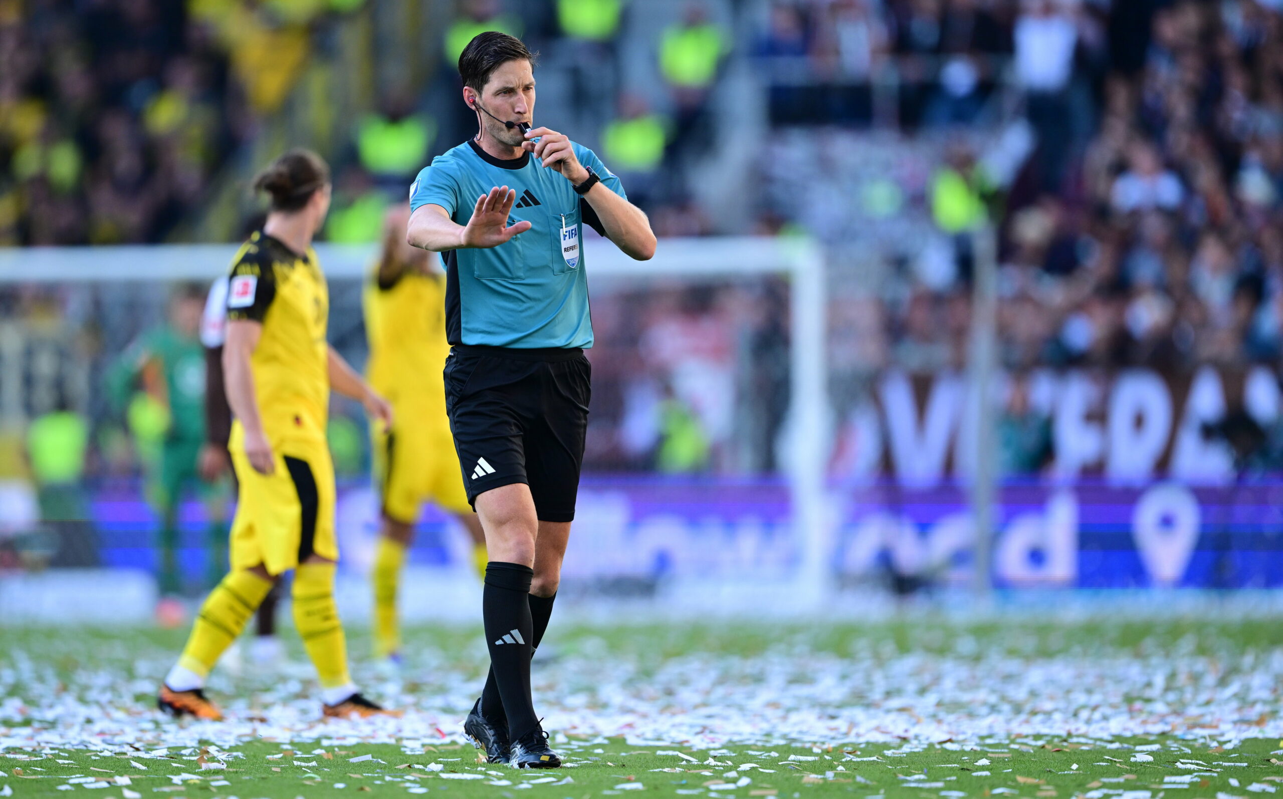 Schiedsrichter Matthias Jöllenbeck auf dem mit Konfetti übersäten Platz.