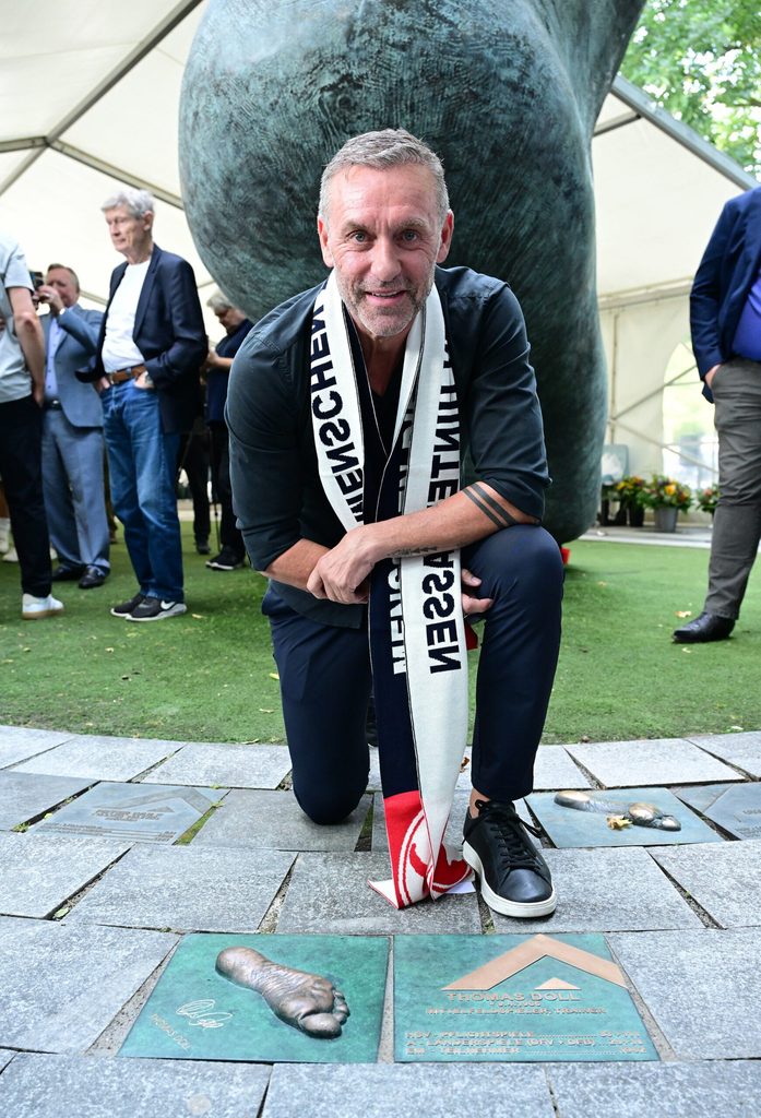Thomas Doll kniet vor seinem Fußabdruck am „Walk of Fame“
