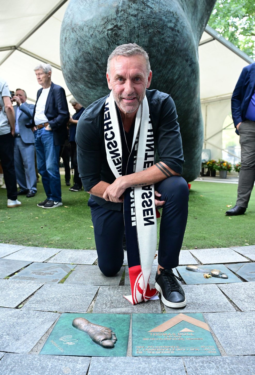 Thomas Doll kniet vor seinem Fußabdruck am „Walk of Fame“