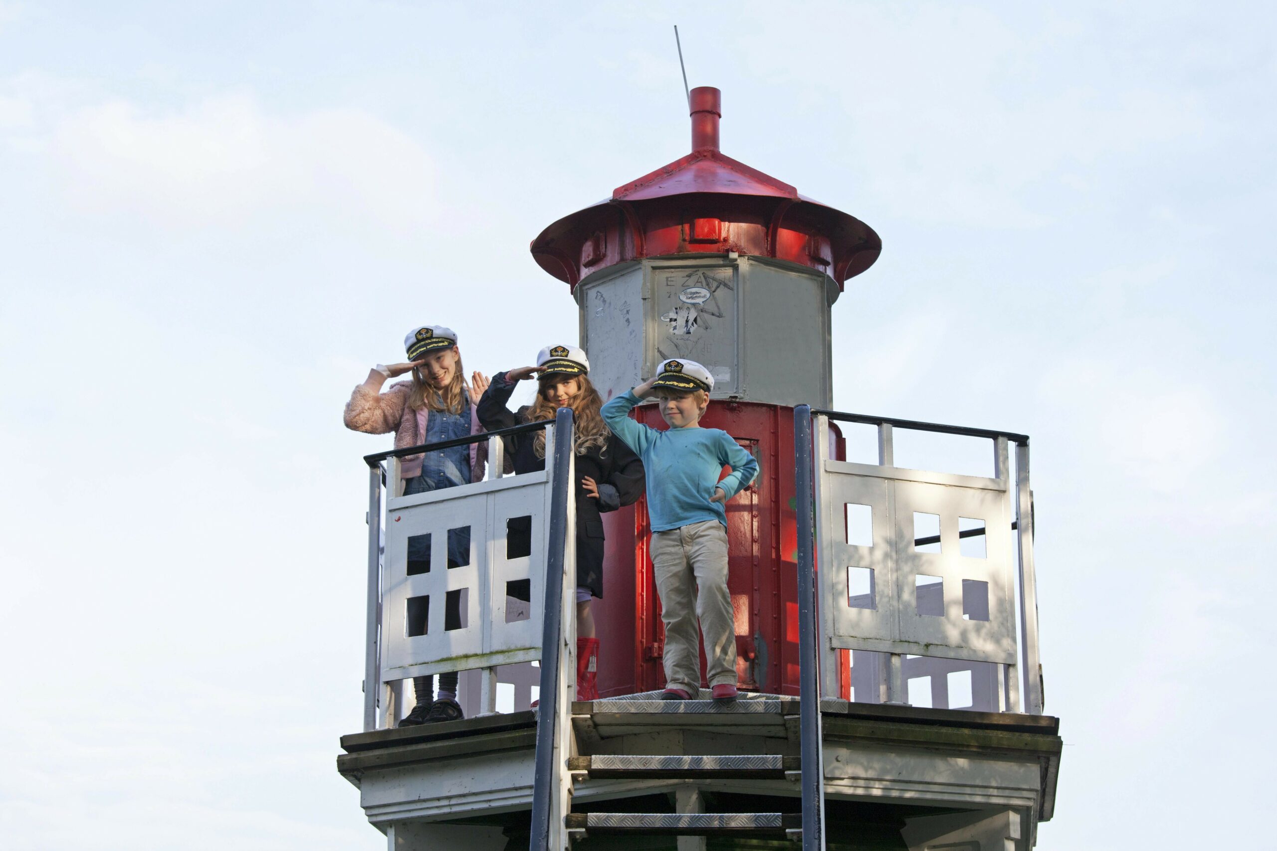 Kinder mit Kapitänsmützen Leuchtturm