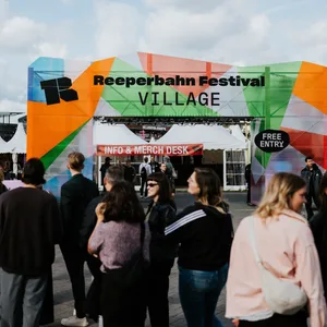 Einfang zum Gelände auf dem Heiligengeistfeld, man kann „Reeperbahn Festival Village, free entry“ lesen, davor stehen Menschen