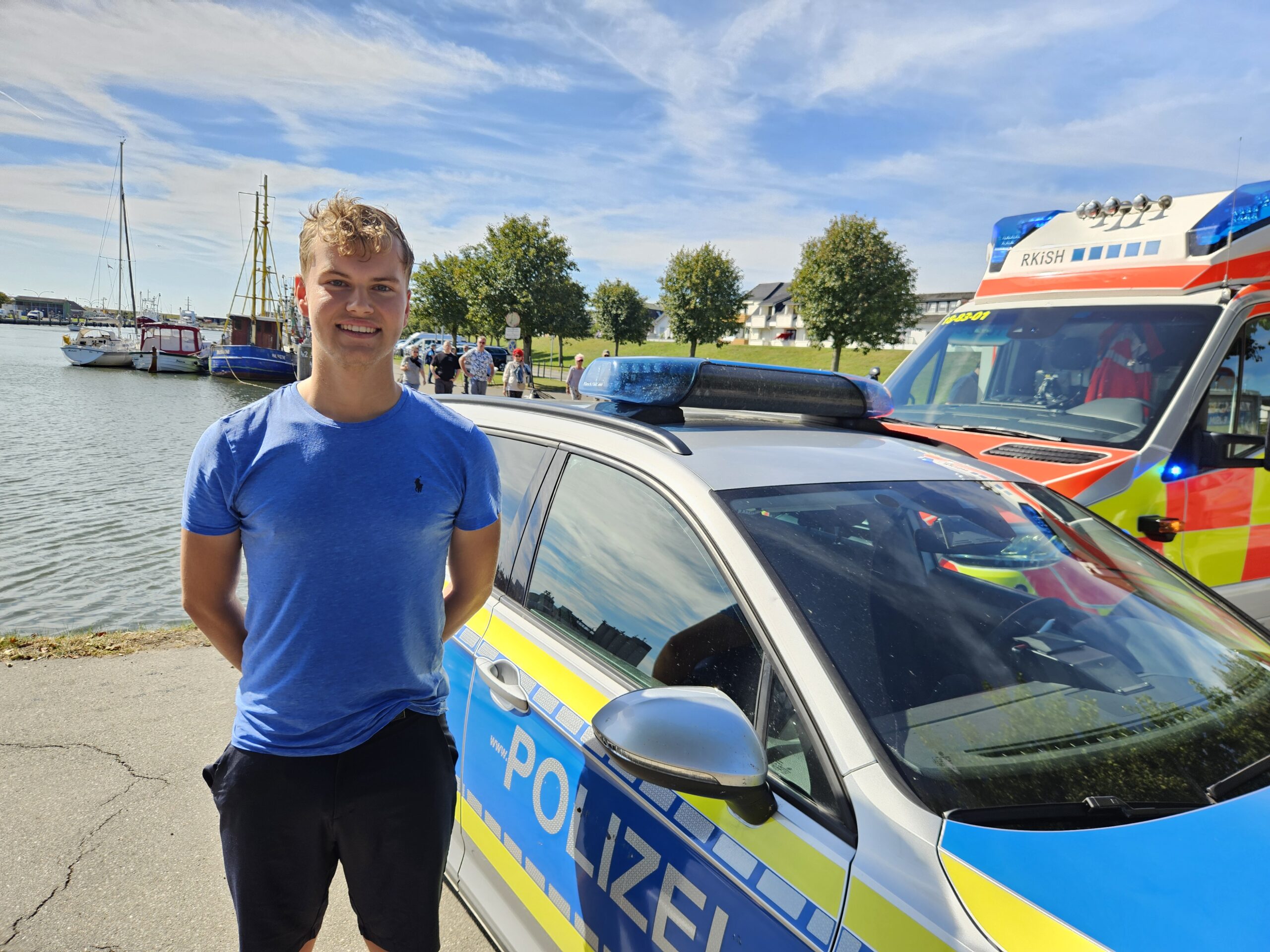 Ein junger Mann steht vor dem Hafenbecken in Büsum.