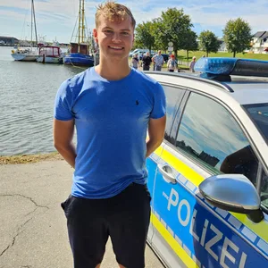 Ein junger Mann steht vor dem Hafenbecken in Büsum.