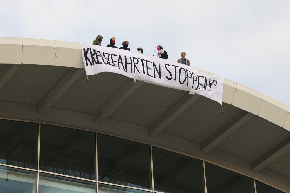 Aktivisten der Gruppe „Widerstand Kollektiv“ rollen auf dem Dach der Hamburger Messehallen Transparente aus.