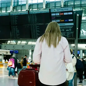 Reisende vor der Hinweis Tafel mit den rot markierten gestrichenen ausgefallene Flügen.