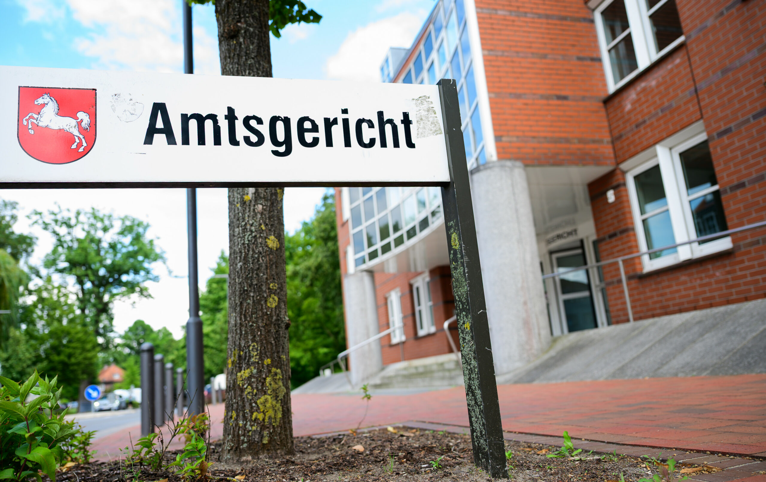 Ein Schild mit der Aufchrift „Amtsgericht“ und dem Wappen von Niedersachsen vor einem Gebäude.