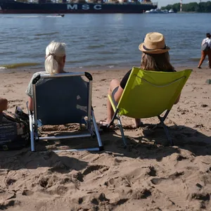 Passanten genießen das Sommerwetter am Elbstrand Ovelgönne.