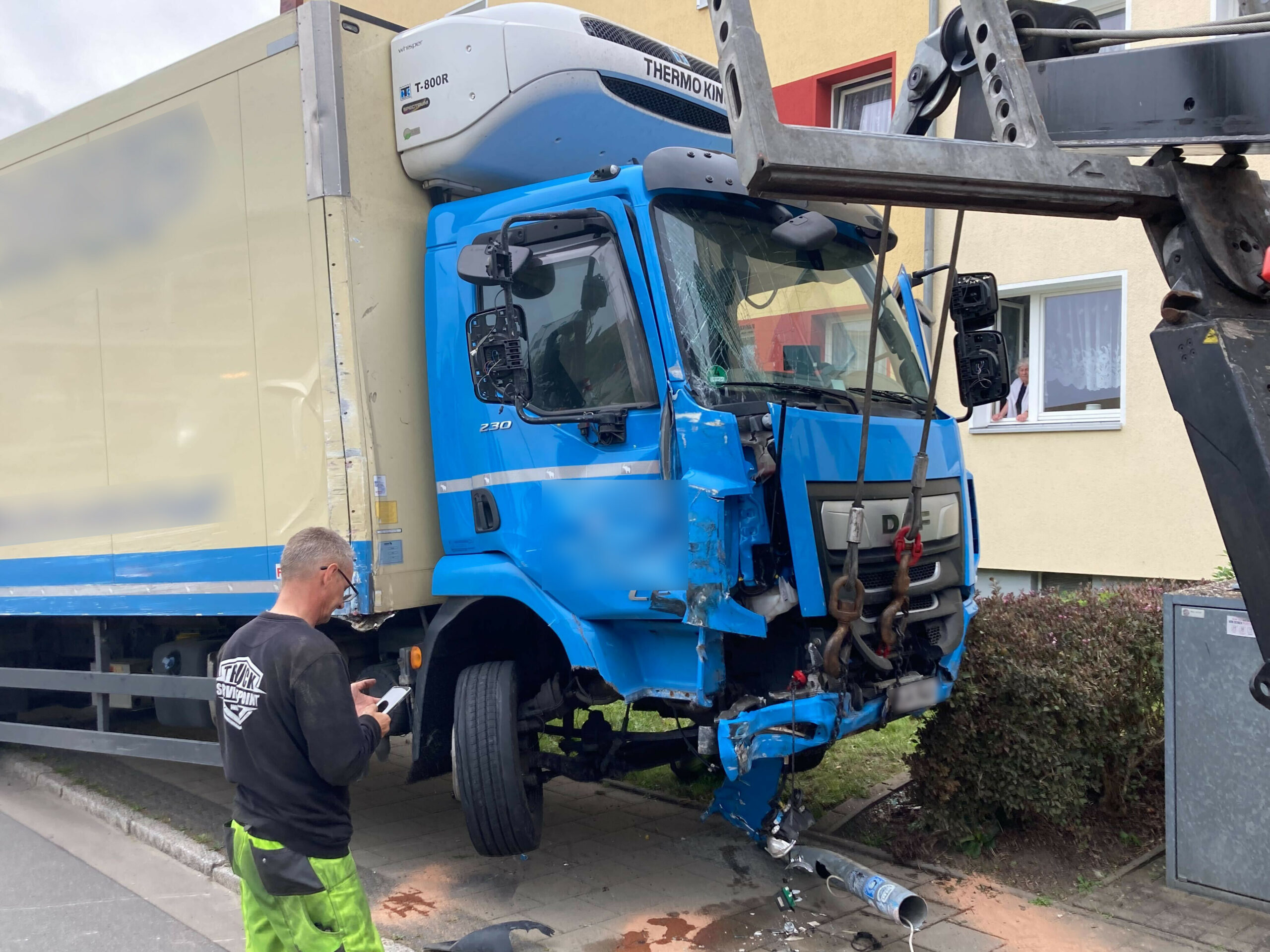 Ein stark beschädigter, blau-beiger Lastwagen wird von der Unfallstelle abtransportiert.