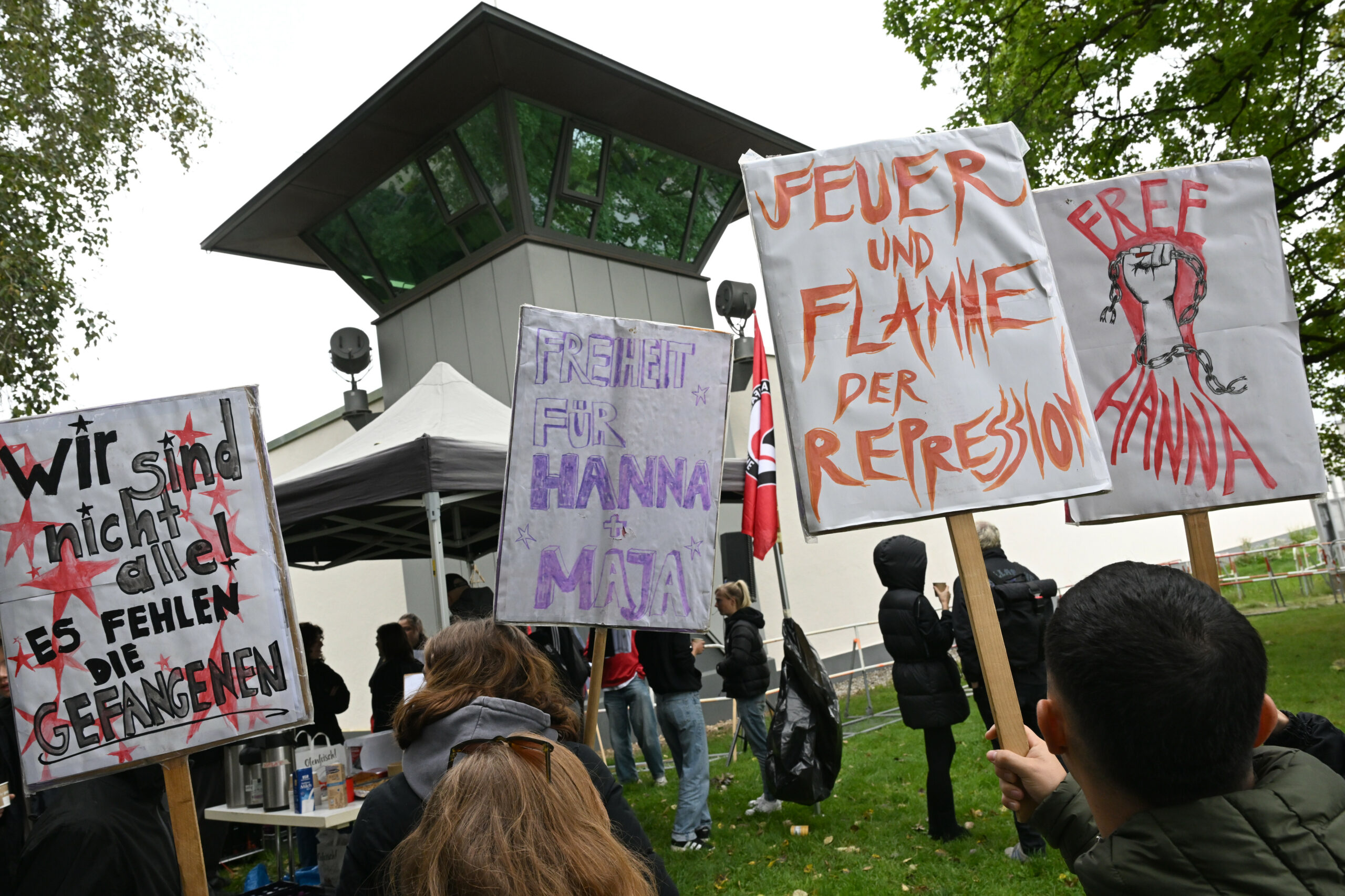Demonstranten stehen mit Schildern bei einer Kundgebung vor der Justizvollzugsanstalt (JVA) Stadelheim, wo in einem Hochsicherheitssaal der Prozess vor dem Oberlandesgericht München gegen eine mutmaßliche Linksextremistin wegen Angriffen auf Neonazis in Budapest stattfindet.