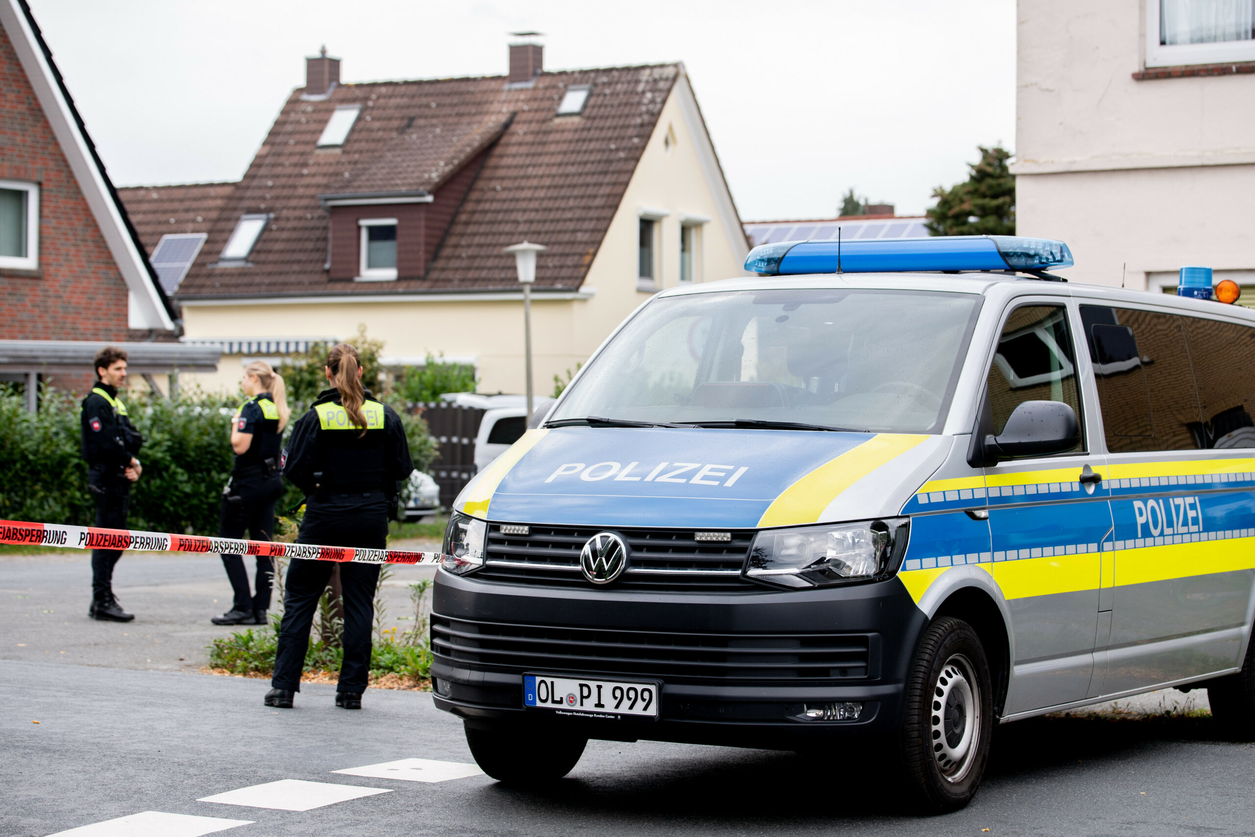 Polizisten stehen hinter einem mit Flatterband abgesperrten Bereich.