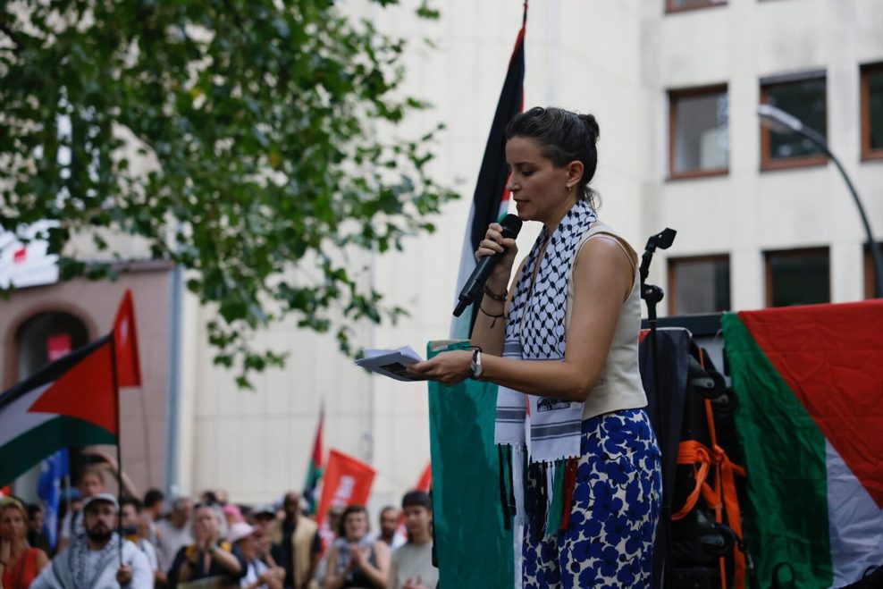 Eine Rednerin der Gruppierung „Jüd*innen gegen den Genozid“ spricht auf einer Bühne zu den Demonstranten.
