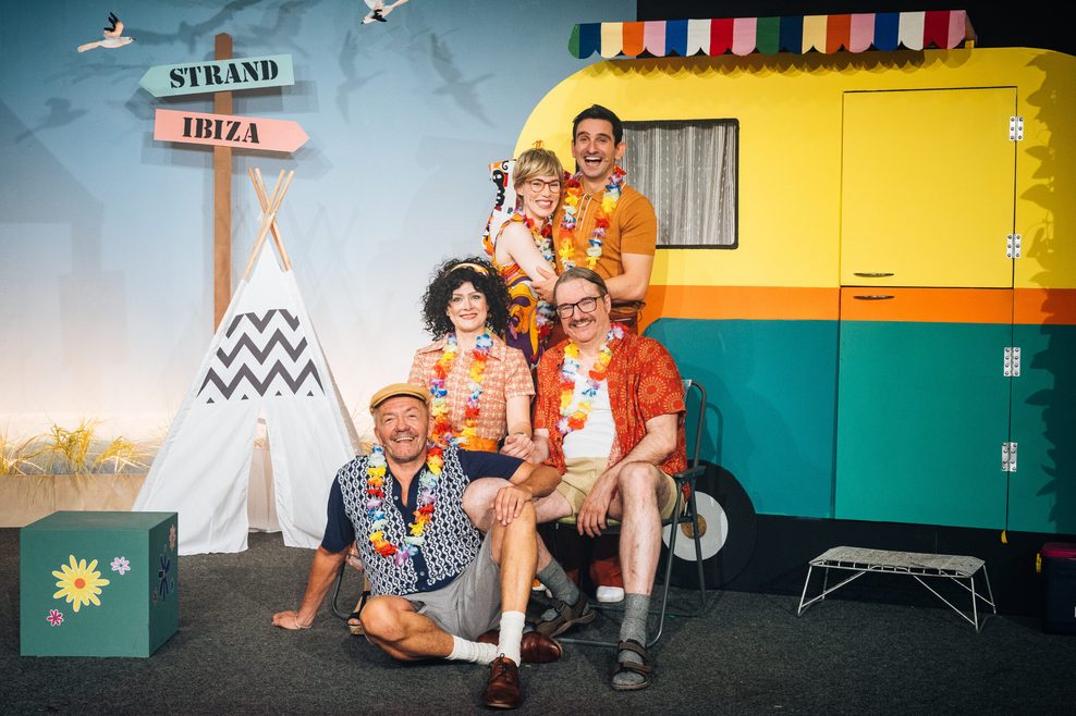 Schauspieler mit sommerlicher Kleidung vor einer Campinglatz-Kulisse