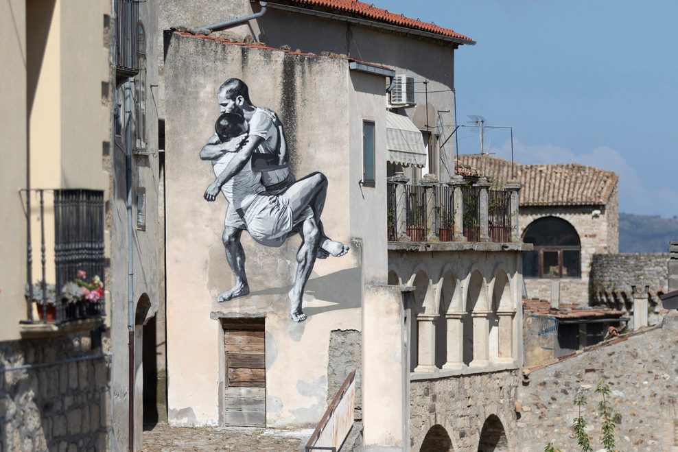 Ein Street-Art-Werk zeigt zwei kämpfende Männer auf einer Hauswand.