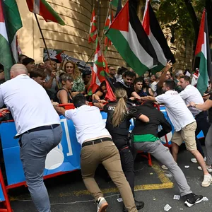 Pro-Palästina-Demonstranten versuchen eine Absperrung zu durchbrechen. Die baskische Polizei und Mitarbeiter der Radsport-Teams versuchen, dies zu verhindern.