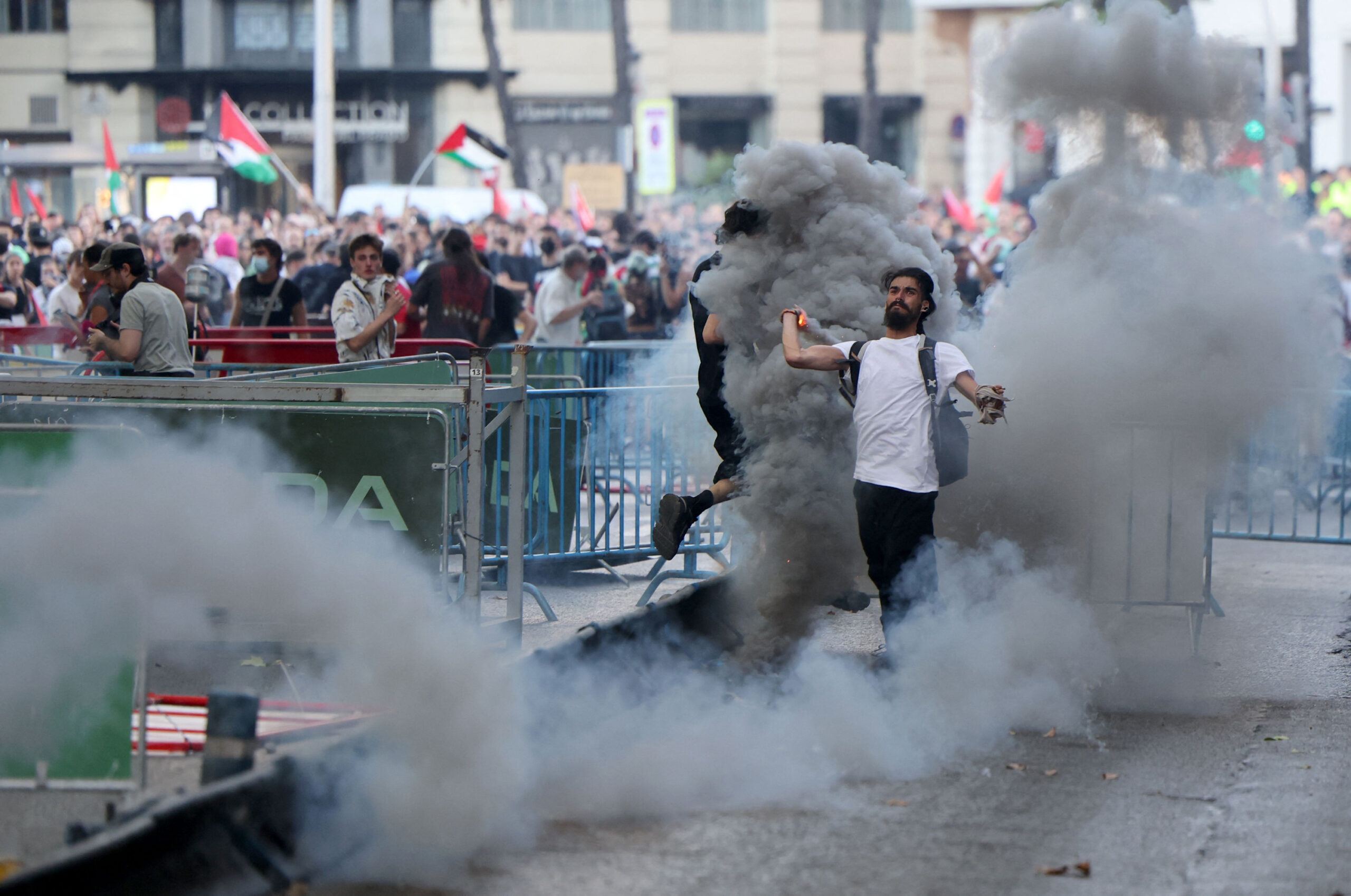 Ein pro-palästinensicher Demonstrant schleudert einen Rauchtopf in Richtung der spanischen Polizei.