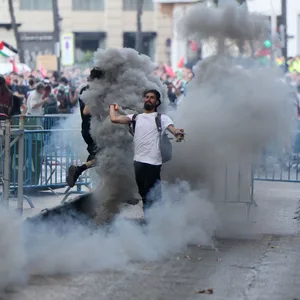 Ein pro-palästinensicher Demonstrant schleudert einen Rauchtopf in Richtung der spanischen Polizei.