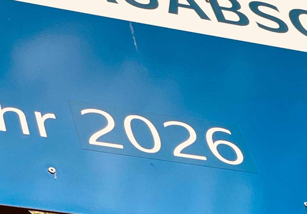 Das Bauschild von nahem. Man erkennt, dass die 2026 auf das Schild geklebt wurde.