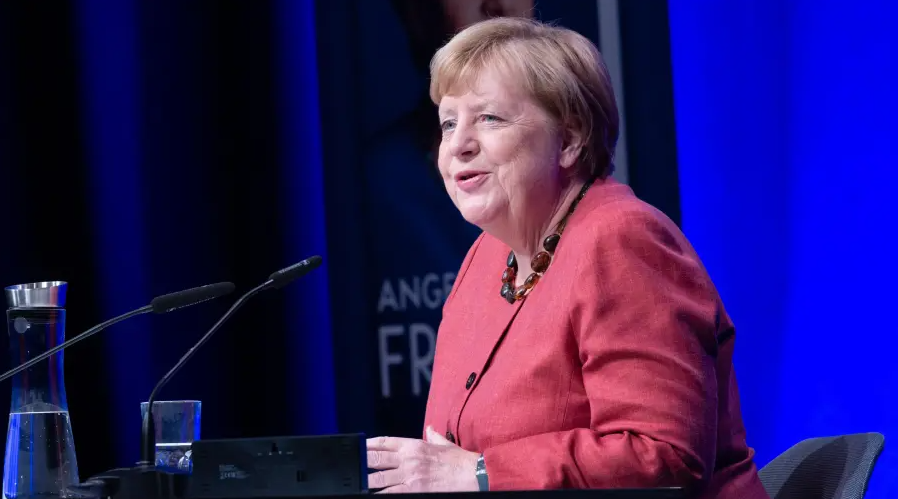 Angela Merkel im hell-roten Anzug bei ihrer Lesung in Osnabrück.