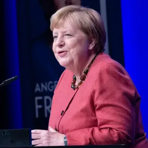 Angela Merkel im hell-roten Anzug bei ihrer Lesung in Osnabrück.