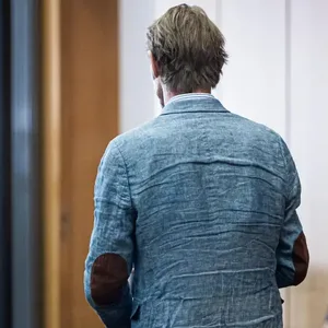 Christian B. steht mit dem Rücken zur Kamera, links sind zwei Justizbeamte